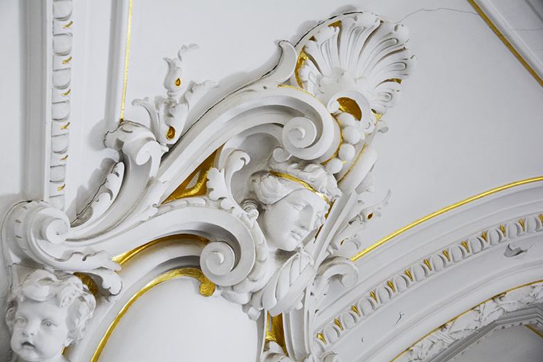 Hauptgebäude/Aula/Stuckatur weiss goldener Kopf/Seitenaufnahme