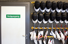 Zentrum für Sport/Fechtausrüstungen an Wand/Türe mit Notausgang