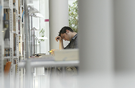 Bibliothek/Innenansicht/Student stützt Kopf ab beim Lernen